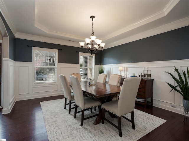 dining room with dark hardwood / wood-style floors, a raised ceiling, and crown molding