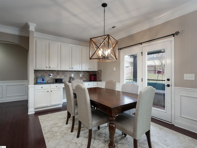 dining space with hardwood / wood-style floors, crown molding, and a chandelier