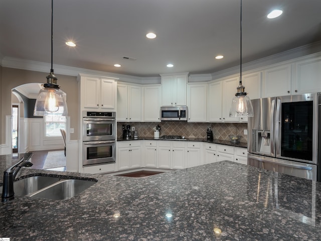 kitchen featuring pendant lighting, white cabinetry, ornamental molding, and appliances with stainless steel finishes