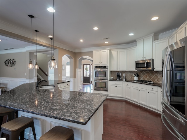 kitchen featuring sink, dark wood-type flooring, decorative light fixtures, appliances with stainless steel finishes, and ornamental molding