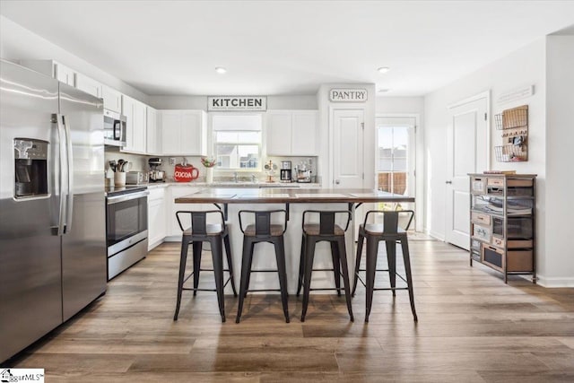 kitchen with white cabinetry, appliances with stainless steel finishes, a center island, and a kitchen breakfast bar