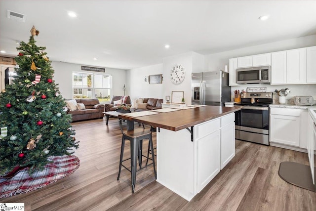 kitchen featuring white cabinetry, appliances with stainless steel finishes, butcher block counters, and light hardwood / wood-style floors