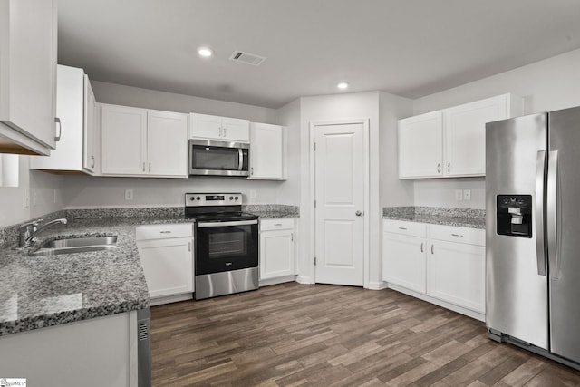 kitchen featuring dark wood-type flooring, white cabinets, sink, dark stone countertops, and stainless steel appliances