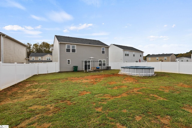 back of house featuring a fenced in pool, a yard, and a gazebo