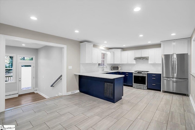 kitchen featuring kitchen peninsula, appliances with stainless steel finishes, light wood-type flooring, blue cabinets, and white cabinets