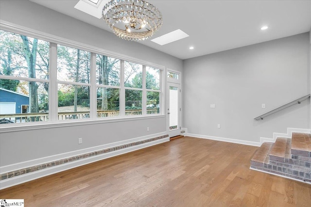 unfurnished living room featuring hardwood / wood-style flooring, a notable chandelier, and a baseboard radiator