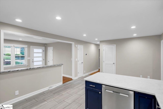 kitchen featuring blue cabinetry, light stone countertops, stainless steel dishwasher, and light wood-type flooring