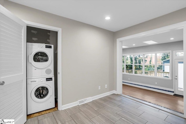 laundry room featuring stacked washer / drying machine, light hardwood / wood-style floors, and a baseboard radiator