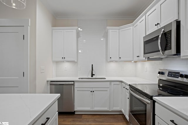 kitchen with white cabinetry, sink, dark wood-type flooring, appliances with stainless steel finishes, and ornamental molding