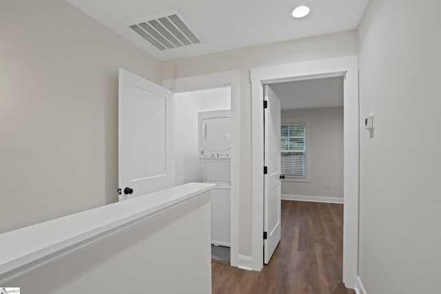 corridor with dark hardwood / wood-style flooring and stacked washer and dryer