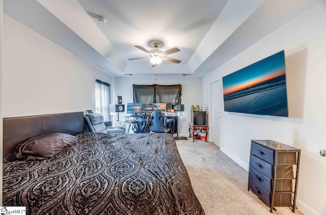 carpeted bedroom featuring a raised ceiling and ceiling fan