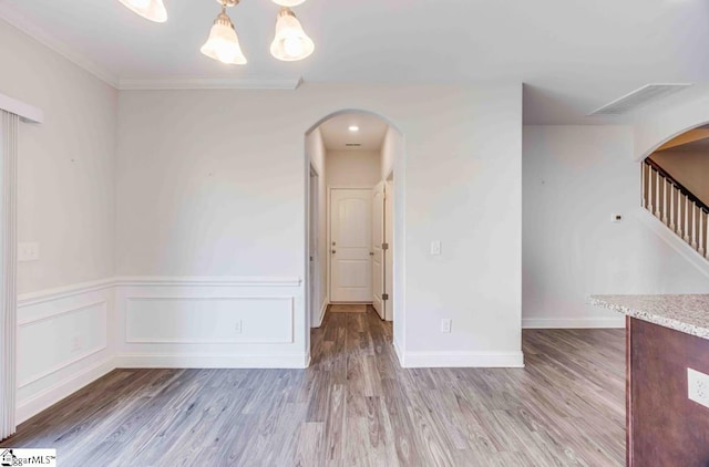 unfurnished room with wood-type flooring, crown molding, and a notable chandelier