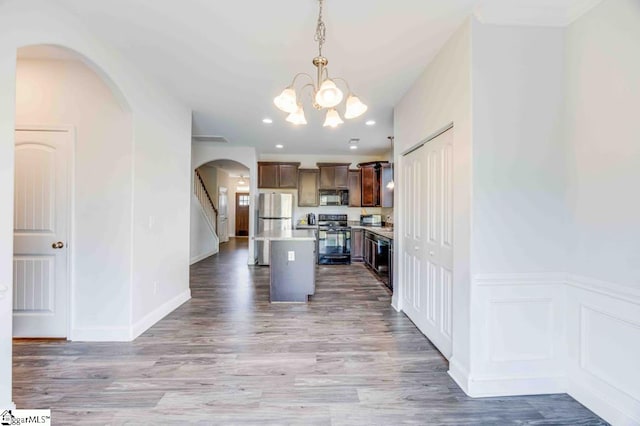 kitchen featuring light hardwood / wood-style floors, a kitchen island, hanging light fixtures, and black appliances