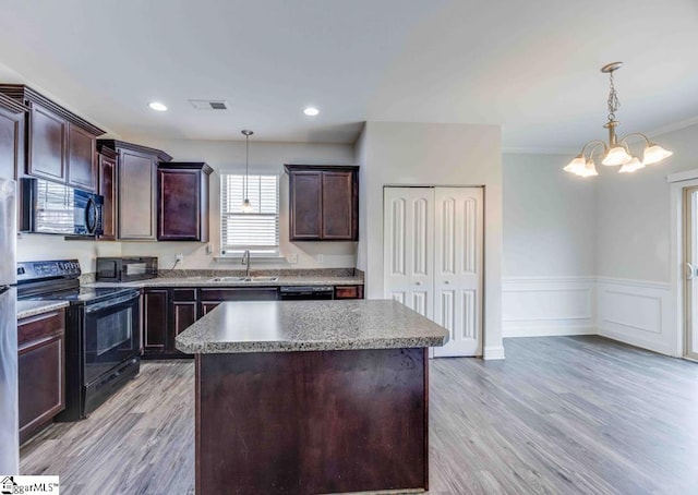 kitchen featuring pendant lighting, a kitchen island, black appliances, and sink