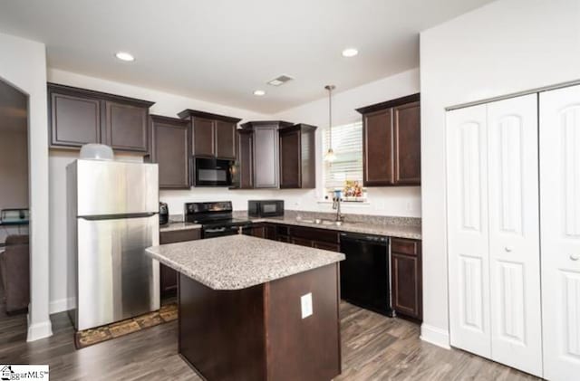 kitchen with dark wood-type flooring, black appliances, sink, decorative light fixtures, and a kitchen island