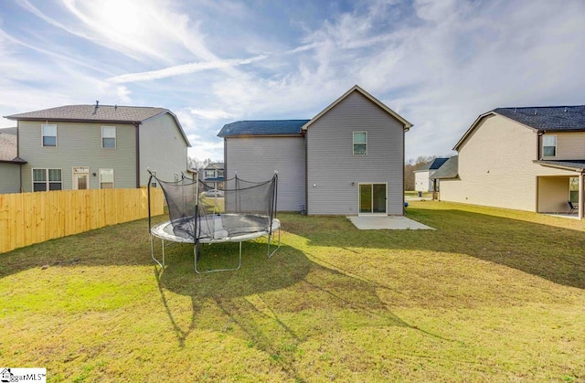 back of property featuring a trampoline and a lawn