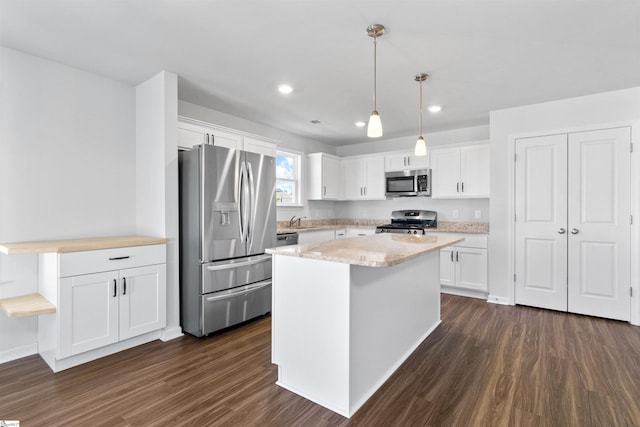 kitchen featuring appliances with stainless steel finishes, a kitchen island, white cabinetry, and pendant lighting