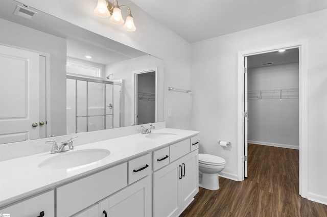 bathroom with hardwood / wood-style floors, vanity, toilet, and walk in shower