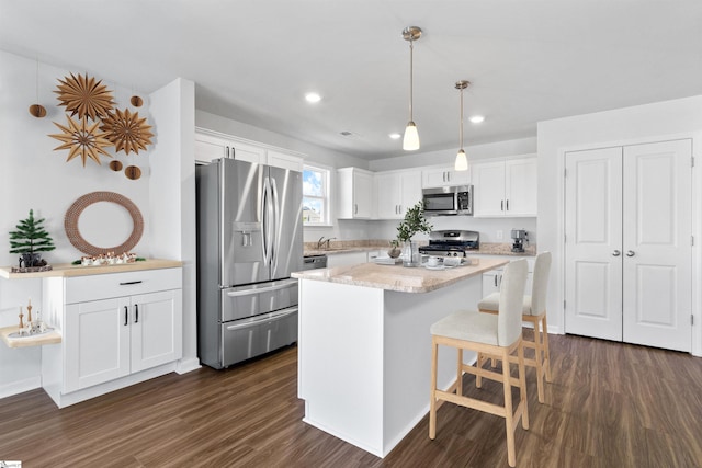 kitchen featuring hanging light fixtures, stainless steel appliances, a kitchen island, dark hardwood / wood-style floors, and white cabinets