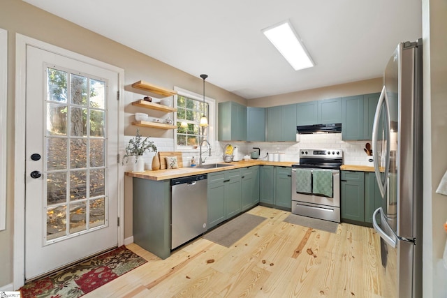 kitchen with appliances with stainless steel finishes, backsplash, light hardwood / wood-style flooring, and butcher block counters