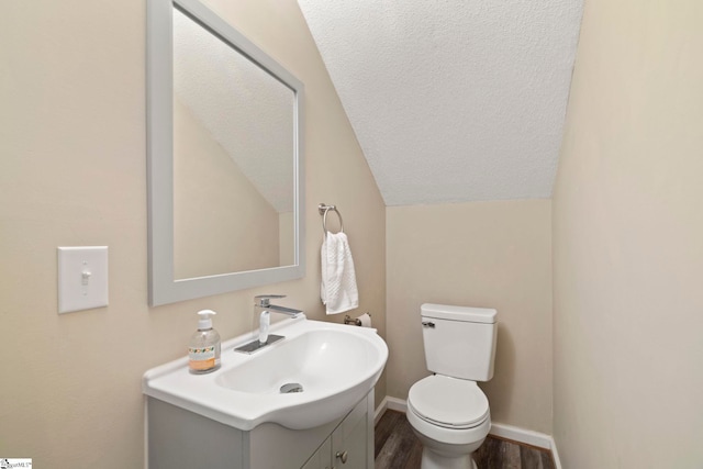 bathroom featuring hardwood / wood-style floors, vanity, toilet, and lofted ceiling