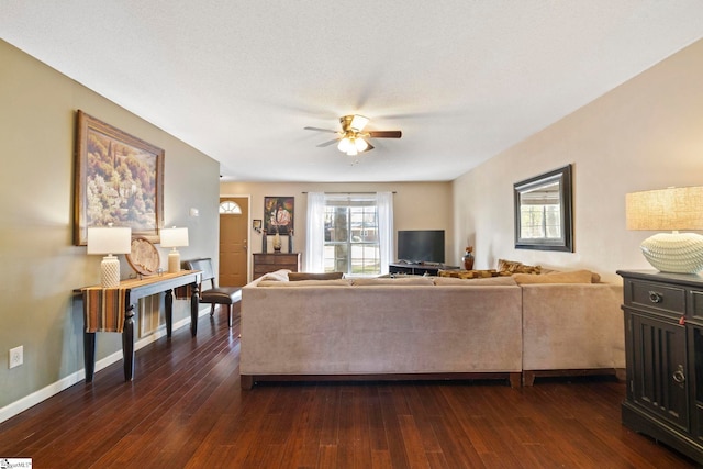 living room featuring ceiling fan, dark wood-type flooring, and a textured ceiling