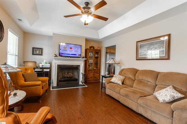 living room with hardwood / wood-style floors, ceiling fan, and a tray ceiling