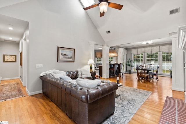 living room featuring hardwood / wood-style flooring, high vaulted ceiling, ceiling fan, and decorative columns