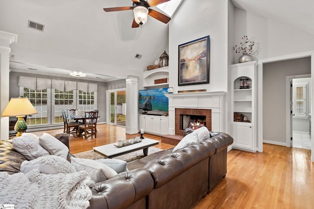 living room with high vaulted ceiling, light hardwood / wood-style flooring, ceiling fan, built in shelves, and a fireplace