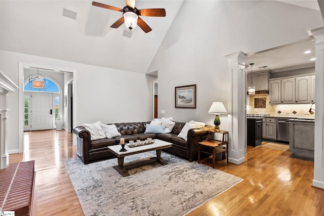 living room featuring high vaulted ceiling, sink, ceiling fan, light hardwood / wood-style floors, and decorative columns