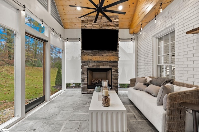 unfurnished sunroom with a fireplace, ceiling fan, a healthy amount of sunlight, and wood ceiling