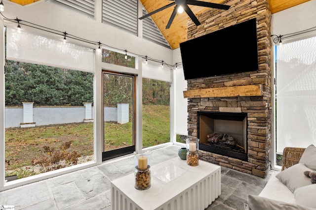 sunroom featuring ceiling fan, wood ceiling, a fireplace, and vaulted ceiling