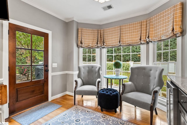 sitting room featuring wine cooler, light hardwood / wood-style flooring, and ornamental molding