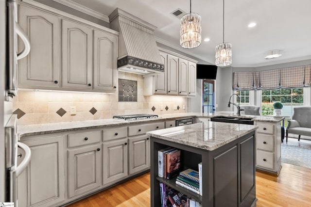 kitchen with sink, a center island, stainless steel appliances, light wood-type flooring, and ornamental molding