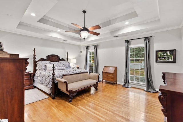 bedroom with ornamental molding, a tray ceiling, ceiling fan, and light hardwood / wood-style floors