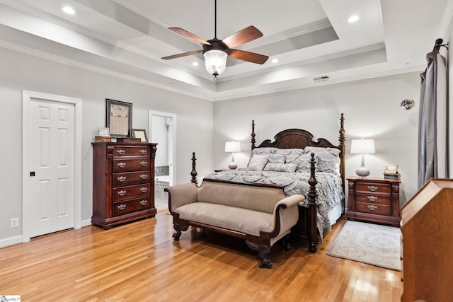 bedroom with ceiling fan, crown molding, a tray ceiling, and light hardwood / wood-style flooring