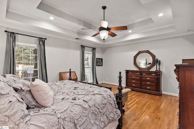 bedroom with a tray ceiling, light hardwood / wood-style flooring, ceiling fan, and ornamental molding