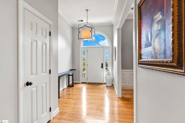 foyer with light wood-type flooring and crown molding