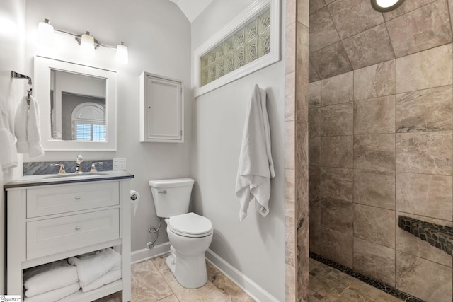 bathroom with a tile shower, vanity, toilet, and tile patterned floors