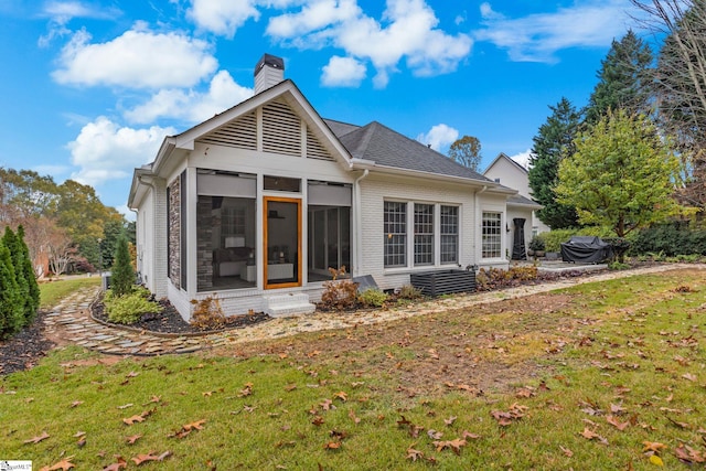 rear view of property with a lawn and a sunroom