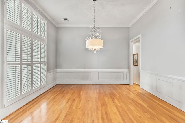 unfurnished room featuring crown molding, hardwood / wood-style flooring, and an inviting chandelier