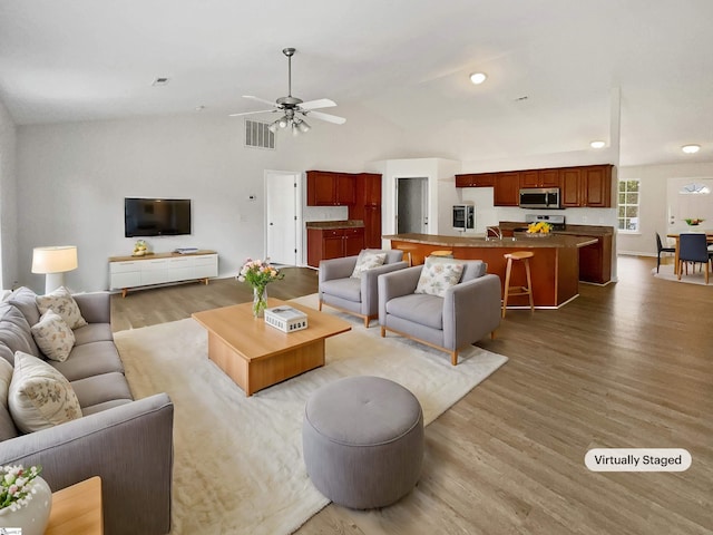 living room with ceiling fan, hardwood / wood-style floors, lofted ceiling, and sink