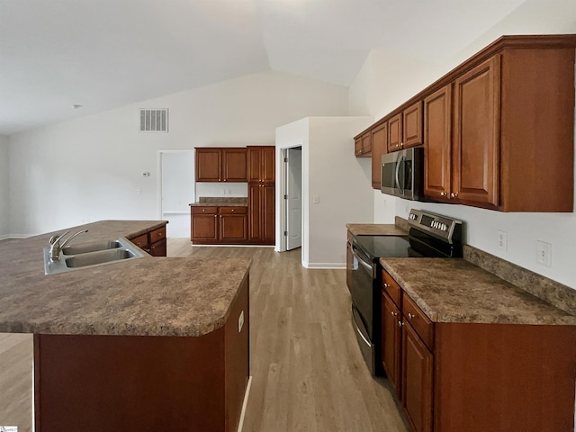 kitchen featuring lofted ceiling, a kitchen island with sink, sink, electric range, and light hardwood / wood-style floors