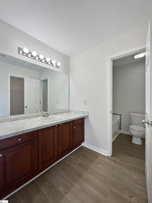 bathroom featuring a bathtub, vanity, wood-type flooring, and toilet