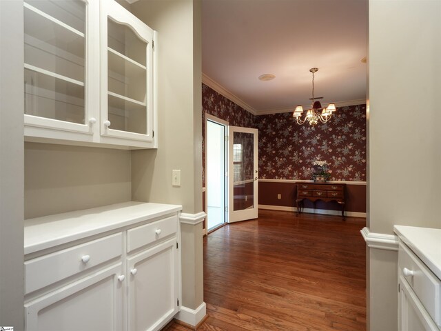 kitchen with dark wood-type flooring, white cabinets, ornamental molding, decorative light fixtures, and a chandelier