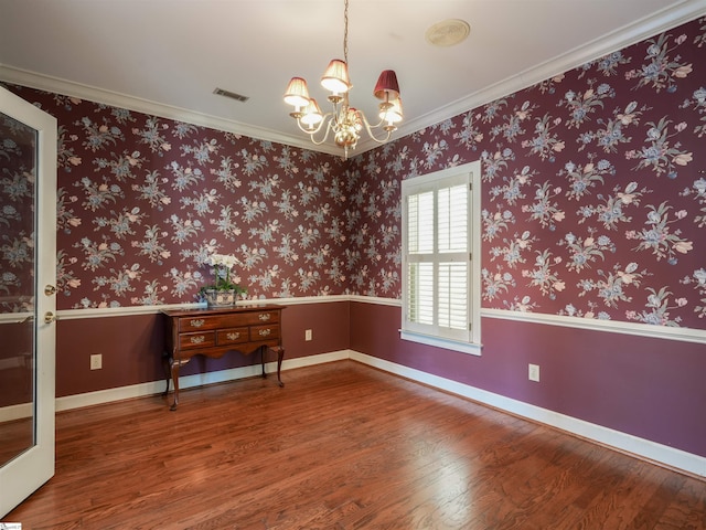 spare room featuring a chandelier, hardwood / wood-style floors, and crown molding