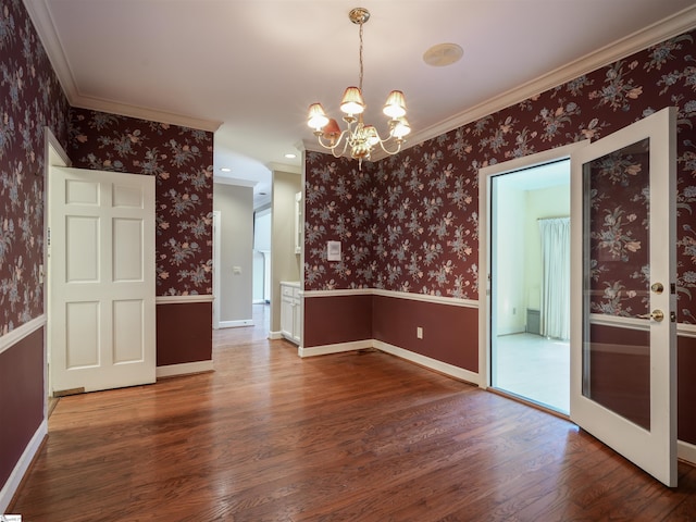 spare room featuring crown molding, dark wood-type flooring, and a notable chandelier