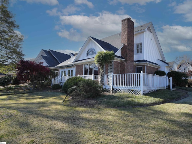 rear view of property featuring a lawn and a deck