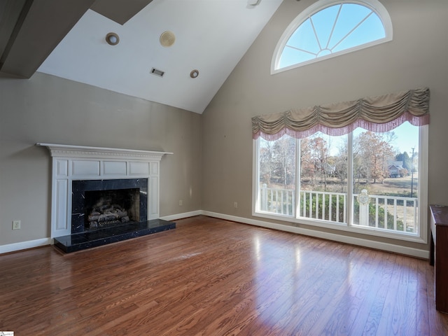 unfurnished living room with a healthy amount of sunlight, dark hardwood / wood-style flooring, and high vaulted ceiling