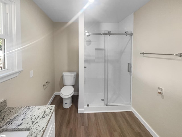 bathroom featuring vanity, hardwood / wood-style flooring, toilet, and walk in shower